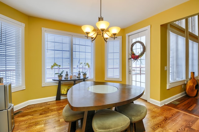 dining area with wood-type flooring and an inviting chandelier