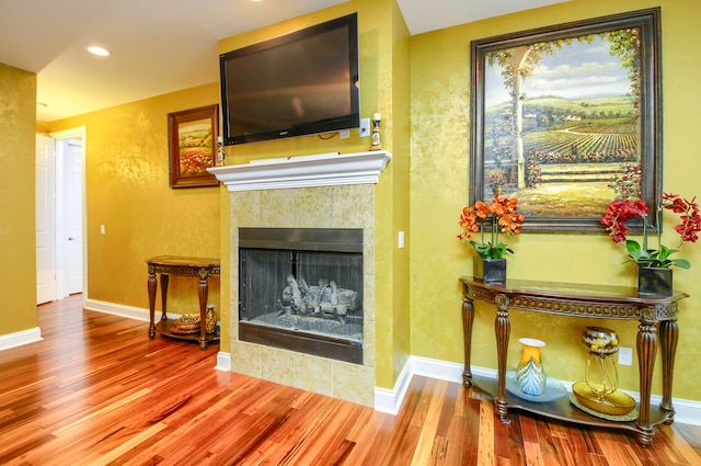 unfurnished living room featuring hardwood / wood-style flooring and a tiled fireplace