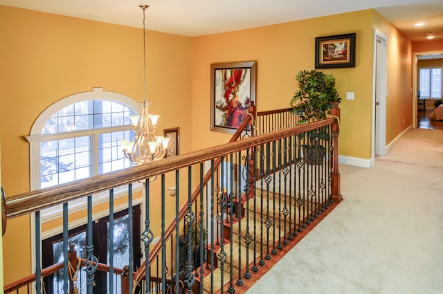 hallway with an inviting chandelier and carpet