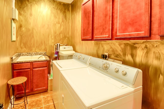 clothes washing area with washer and dryer, cabinets, and light tile patterned floors