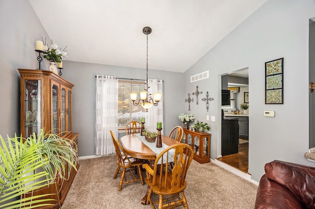 carpeted dining room with vaulted ceiling and a chandelier