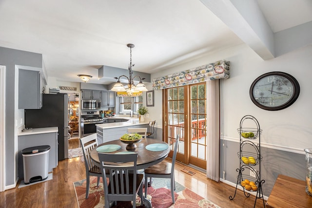 dining room featuring beamed ceiling, hardwood / wood-style floors, and a chandelier