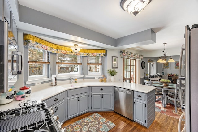 kitchen featuring sink, kitchen peninsula, plenty of natural light, a notable chandelier, and appliances with stainless steel finishes