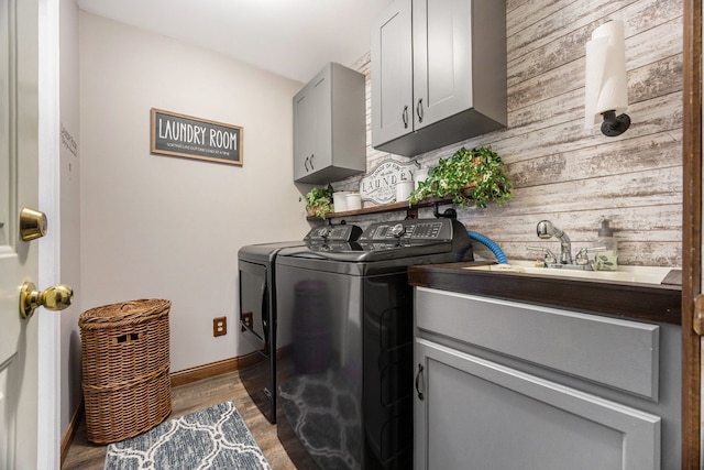 laundry room with cabinets, washer and clothes dryer, wood walls, and wood-type flooring