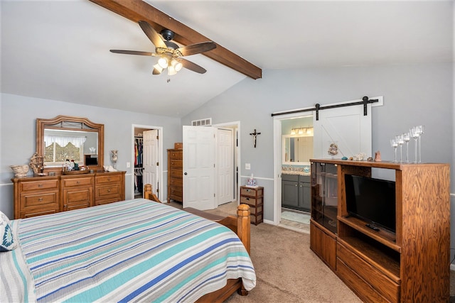 carpeted bedroom with ceiling fan, a closet, a barn door, a walk in closet, and ensuite bath