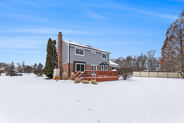 snow covered back of property with a deck