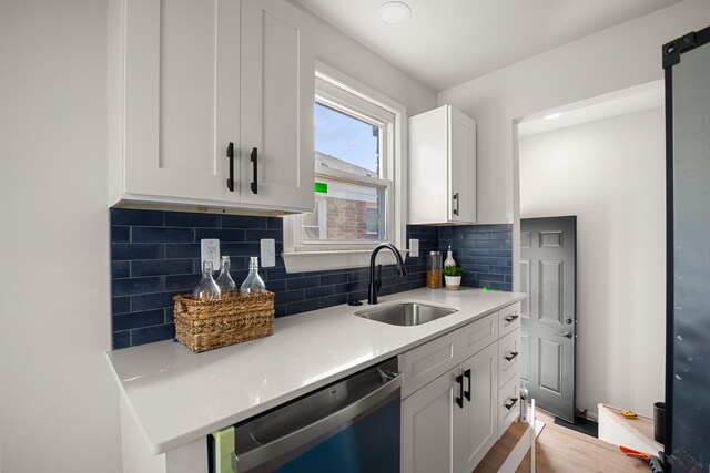 kitchen with white cabinets, stainless steel dishwasher, decorative backsplash, and sink