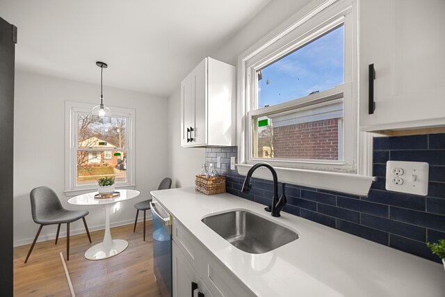 kitchen with dishwasher, decorative backsplash, plenty of natural light, white cabinets, and sink