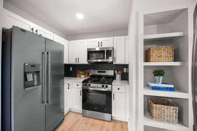 kitchen featuring light hardwood / wood-style flooring, stainless steel appliances, white cabinetry, and backsplash