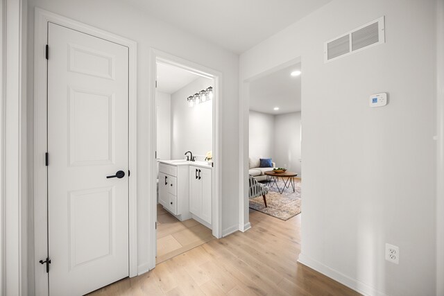 hall with light hardwood / wood-style flooring and sink