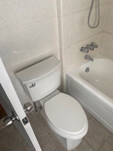 bathroom featuring toilet, tile walls, tile patterned floors, and shower / bath combination