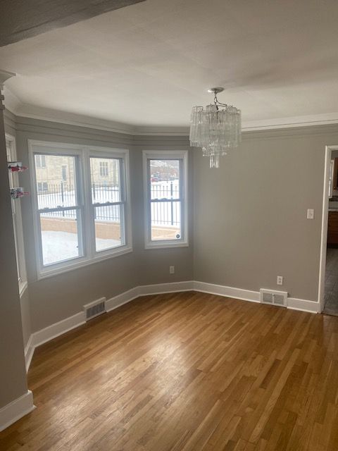 unfurnished room featuring ornamental molding, a chandelier, and hardwood / wood-style flooring