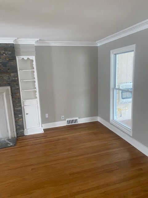 unfurnished living room with dark hardwood / wood-style flooring, plenty of natural light, and crown molding