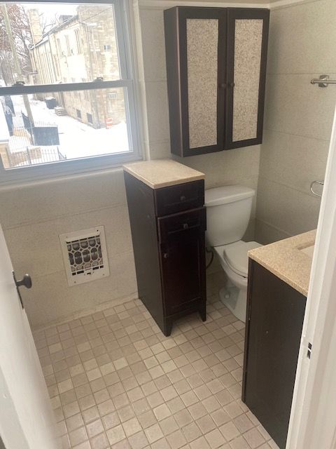 bathroom featuring vanity, tile patterned flooring, toilet, and tile walls