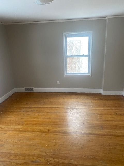 unfurnished room featuring ornamental molding and light wood-type flooring