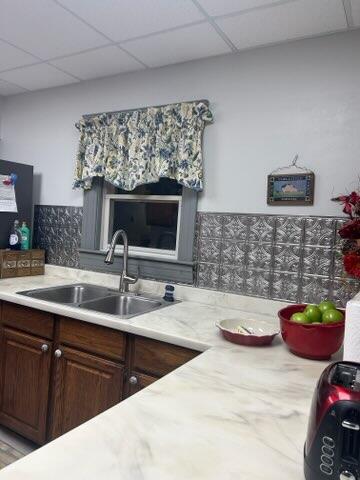 kitchen with a drop ceiling, dark brown cabinets, and sink