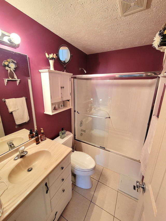 full bathroom with vanity, a textured ceiling, tile patterned flooring, toilet, and bath / shower combo with glass door