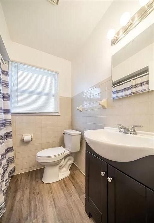 bathroom featuring toilet, vanity, tile walls, and hardwood / wood-style flooring