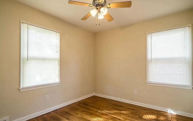 unfurnished room with ceiling fan, a healthy amount of sunlight, and dark wood-type flooring