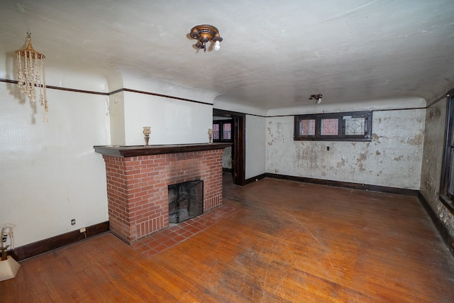 unfurnished living room with a brick fireplace and dark hardwood / wood-style floors