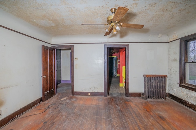 unfurnished room featuring a textured ceiling, ceiling fan, radiator heating unit, and dark hardwood / wood-style floors