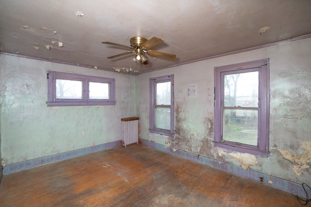 empty room featuring ceiling fan, crown molding, hardwood / wood-style flooring, and radiator