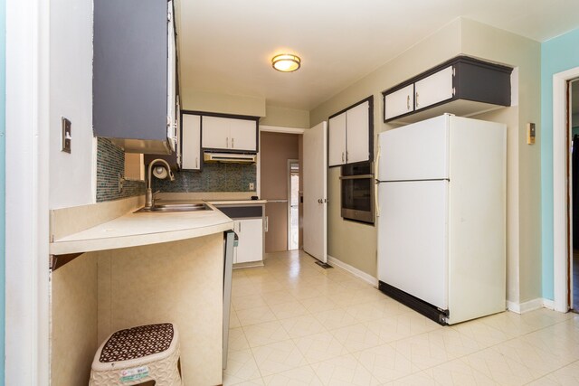 kitchen with sink, white refrigerator, stainless steel oven, and tasteful backsplash