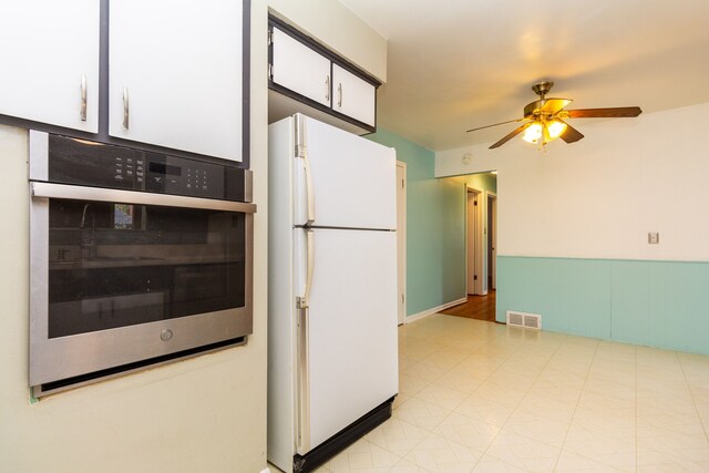 kitchen with ceiling fan, white refrigerator, and white cabinetry