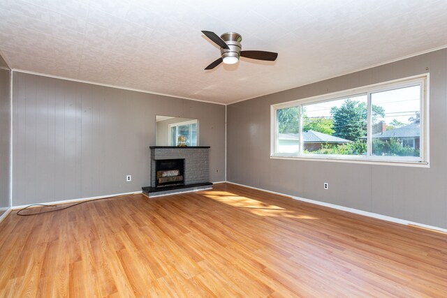 unfurnished living room with a brick fireplace, hardwood / wood-style floors, ceiling fan, and ornamental molding