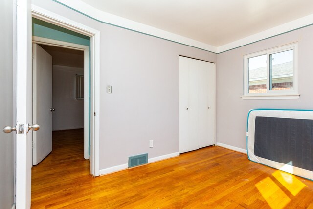 unfurnished bedroom with a closet, heating unit, and wood-type flooring