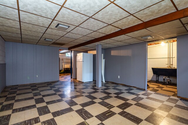 basement featuring white refrigerator, wood walls, and sink