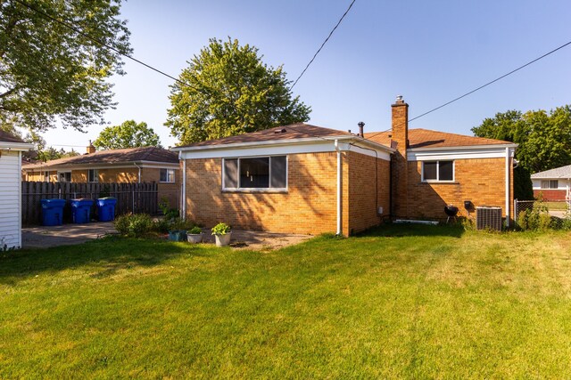 back of house with a yard and central AC