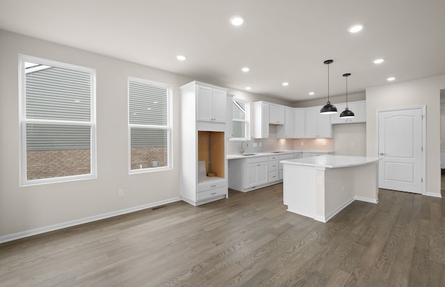 kitchen featuring white cabinets, a kitchen island, light countertops, and hanging light fixtures