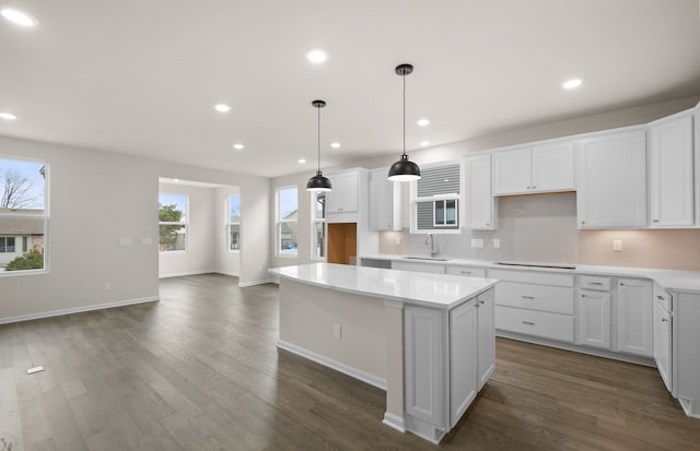 kitchen with light countertops, a kitchen island, a sink, and white cabinetry