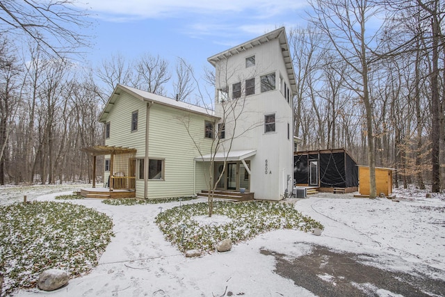 snow covered back of property featuring central AC