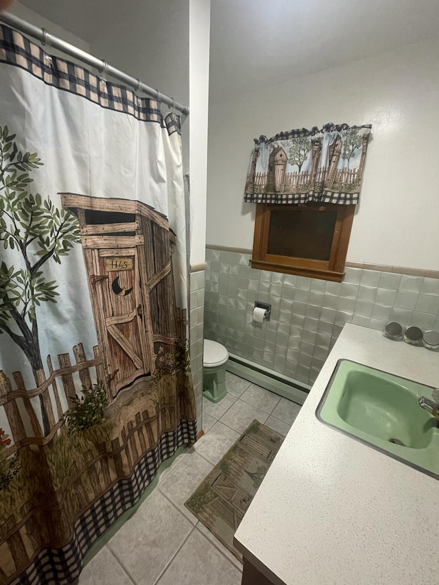 bathroom featuring tile patterned flooring, tile walls, toilet, a baseboard heating unit, and vanity