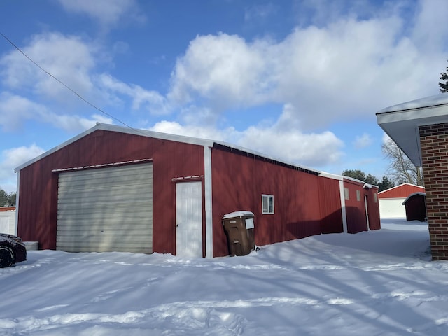 snow covered structure featuring a garage