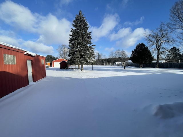 yard covered in snow with a garage and an outdoor structure