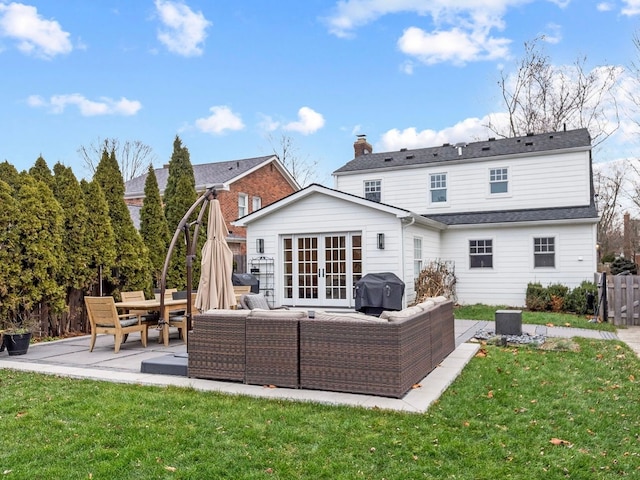 rear view of property with a lawn, french doors, an outdoor living space, and a patio