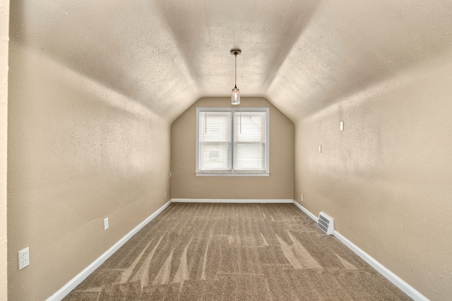 additional living space with a textured ceiling, lofted ceiling, and carpet flooring