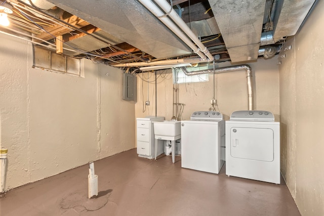 basement featuring separate washer and dryer, sink, and electric panel