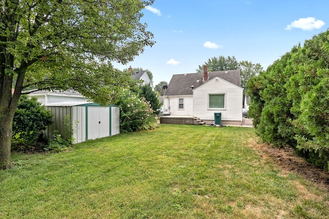 rear view of house featuring a yard and a storage unit