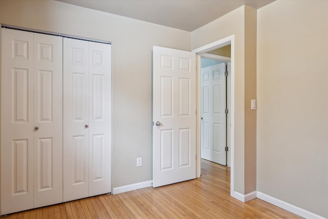 unfurnished bedroom with light wood-type flooring and a closet