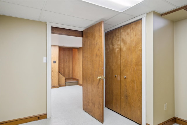 hall with wood walls and a drop ceiling