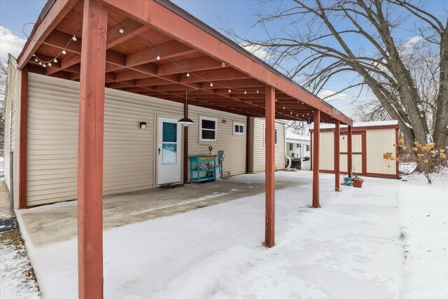 snow covered patio with a shed