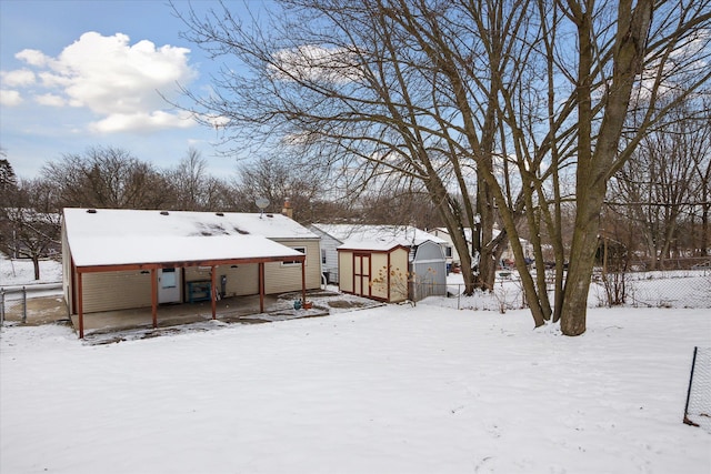 snow covered rear of property featuring a storage unit