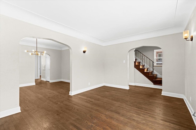 spare room with a notable chandelier, crown molding, and dark hardwood / wood-style flooring