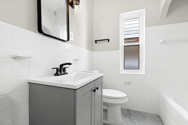 bathroom with tile walls, a tub to relax in, vanity, and toilet