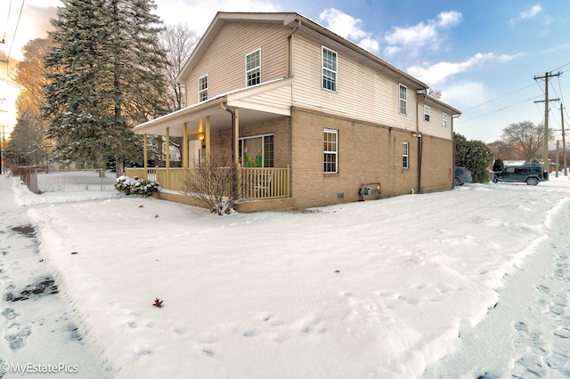 snow covered back of property with a porch