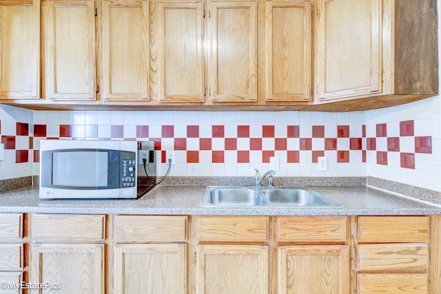 kitchen with light brown cabinetry, decorative backsplash, and sink